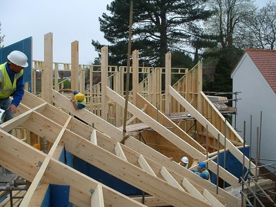 Timber frame under construction with beams being craned in